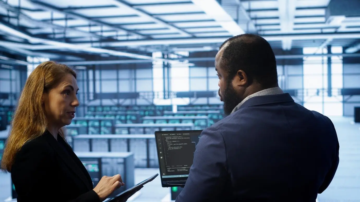 Коллеги из центра обработки данных проводят ежегодное обслуживание, используя ноутбук и планшет.